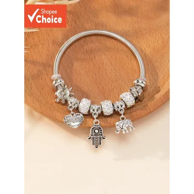 Pulseira prateada de aro em espiral com contas brilhantes e berloques de coração, mão de hamsa, elefante e tartaruga