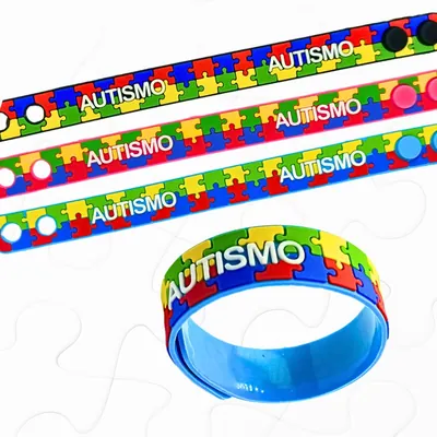 Quatro pulseiras emborrachadas com estampa de quebra-cabeça colorida e a palavra AUTISMO em letras brancas
