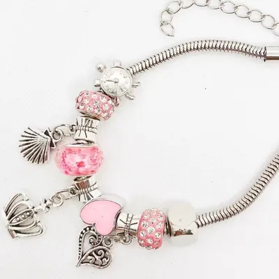 Pulseira prateada de corrente cobrinha com contas rosa, coração, coroa, concha e relógio sobre fundo branco