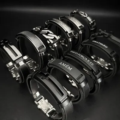 Pulseiras de couro preto com placas de metal: cruz vazada, Amém, Foco Força e Fé e Gratidão, sobre fundo escuro