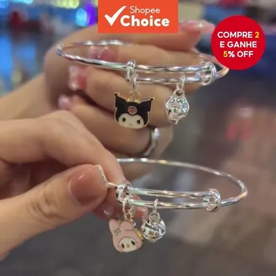 Duas mãos com pulseiras prateadas de aro: uma com personagem preta de caveirinha rosa, outra com coelhinha rosa de laço