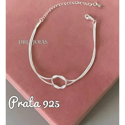 Pulseira de prata com fios finos e um nó circular no centro, fecho de lagosta e corrente extensora, sobre fundo rosa