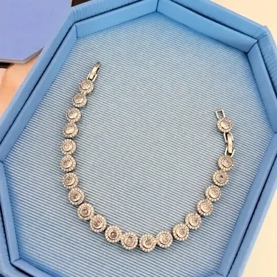 Pulseira prateada de círculos cravejados com pedra central em caixa azul-clara de forro canelado