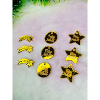 Nove tags douradas espelhadas escritas Feliz Natal, em formato de estrela cadente, círculo e estrela, sobre pelúcia clara