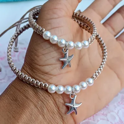 Pulseira e tornozeleira de macramê bege com contas brancas peroladas e pingente de estrela-do-mar na palma da mão