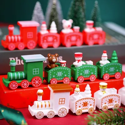 Três trenzinhos de madeira, vermelho, verde e branco, com vagões carregando bonecos de neve, ursos e pinheirinhos