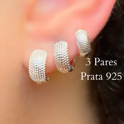 Três argolas largas de prata com textura de pontinhos em relevo usadas em sequência no lóbulo, do maior ao menor