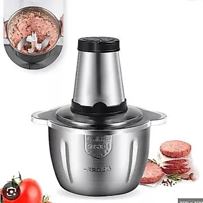 Triturador elétrico com copo de inox, tampa transparente e motor cônico; ao lado, carne moída, hambúrgueres e tomate
