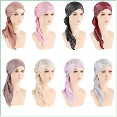 Oito manequins com turbantes pré-amarrados em rosé, rosa, preto, vinho, malva, creme, lilás e prata