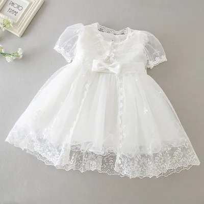 Vestido de bebê marfim com saia de tule, barra de renda floral, laço de cetim na cintura e casaquinho de renda de manga curta