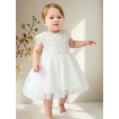 Bebê andando descalça com vestido branco de renda guipir floral no corpo e saia de tule até o joelho