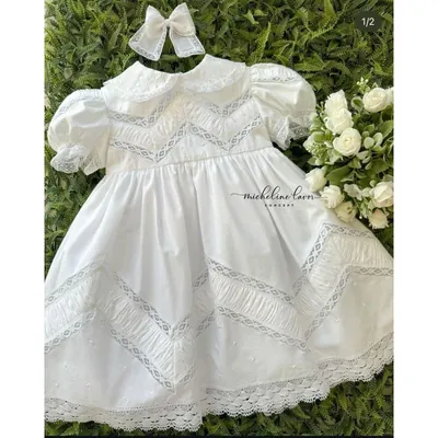 Vestido de batizado branco com gola boneca, mangas bufantes, faixas drapeadas em zigue-zague e barra de renda, com laço