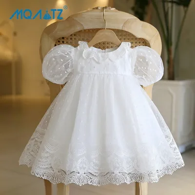 Vestido de bebê branco em tule de bolinhas, com mangas bufantes, gola de renda recortada e barra rendada, num cabide