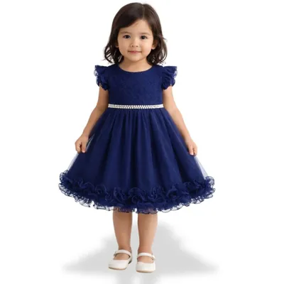 Menina pequena com vestido azul-marinho de renda e tule, cinto de pérolas e barra de babados, de sapatilha branca