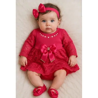 Bebê deitada com vestido vermelho de manga longa em renda, laço de cetim, faixa de cabelo com laço e sapatinhos