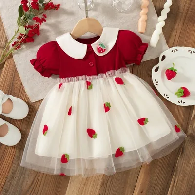 Vestido de bebê com corpo vermelho, gola boneca branca com broche de morango e saia creme transparente com morangos