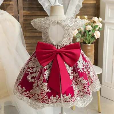 Vestido de bebê em manequim, saia vermelha de tule com bordado dourado, corpo champanhe, costas vazadas e laço vermelho