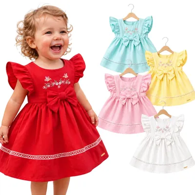 Menina sorrindo com vestido vermelho de babado e laço, ao lado do mesmo modelo em verde-água, amarelo, rosa e branco