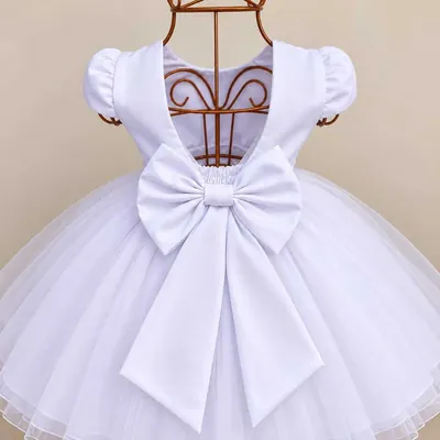 Costas de vestido infantil branco em manequim de arame, com mangas curtas franzidas, laço grande e saia de tule