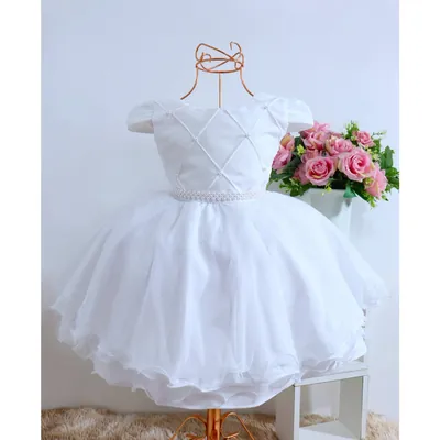 Vestido infantil branco em manequim, corpete com desenho de losangos e pérolas, cinto perolado e saia de tule armada
