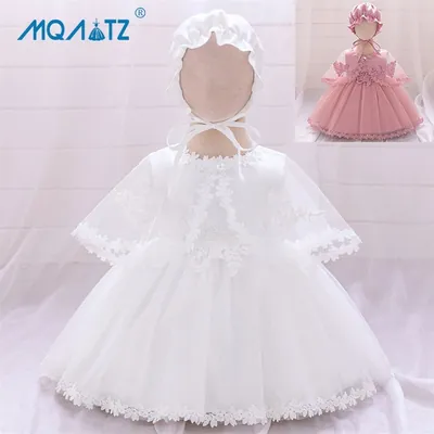 Vestido branco de bebê com capinha de tule, saia com renda e touca de babado em manequim; versão rosa no canto