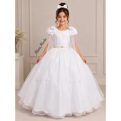 Menina de vestido longo branco com mangas bufantes, capa de tule nas costas, cinto dourado e saia rodada com brilho
