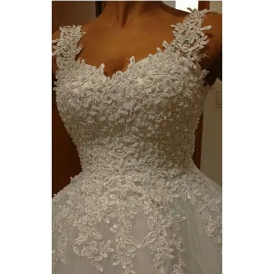 Detalhe do corpete de vestido de noiva marfim com alças de renda, decote coração e flores de renda bordadas com pérolas