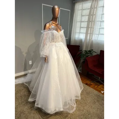 Vestido de noiva branco em manequim, corpete rendado tomara que caia, mangas bufantes de tule soltas e saia de tule com cauda