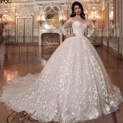 Noiva em salão com lustres, vestido de baile de manga longa, renda branca de folhas sobre fundo nude e cauda longa