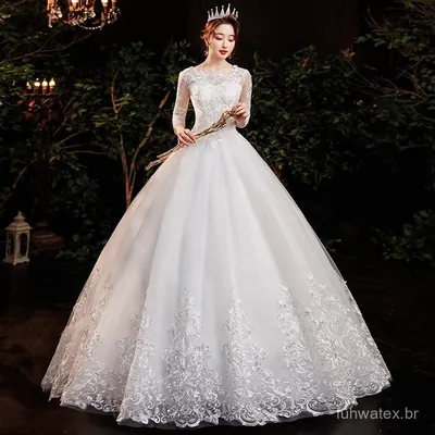 Noiva com tiara em vestido branco de saia ampla de tule, manga longa transparente e barra larga de renda bordada
