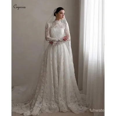 Noiva com vestido branco de renda, gola alta, mangas longas transparentes, saia linha A com cauda e véu longo