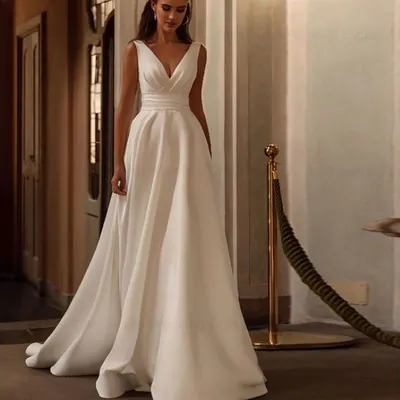 Noiva em corredor de palácio usando vestido branco sem mangas, decote V drapeado, cintura franzida e saia longa lisa