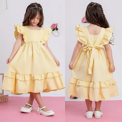 Menina de frente e de costas com vestido amarelo-claro midi, mangas de babado, laço nas costas e sapatilha branca