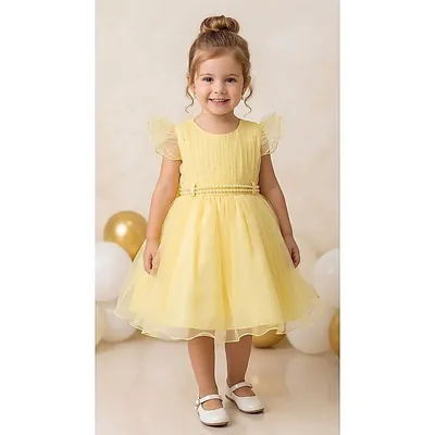 Menina pequena de coque com vestido amarelo de saia rodada, cinto de pérolas e mangas de babado, entre balões