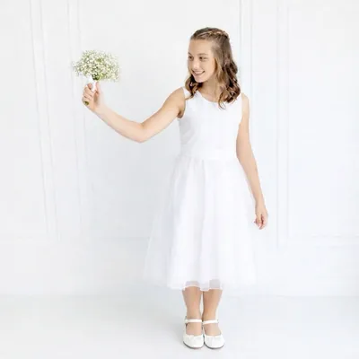 Menina sorridente de vestido branco sem mangas, faixa lisa na cintura e saia midi de tule, com buquê de mosquitinho