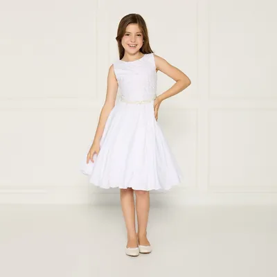 Menina sorridente com vestido branco regata, corpo de renda texturizada, cinto fino de pérolas e saia rodada curta