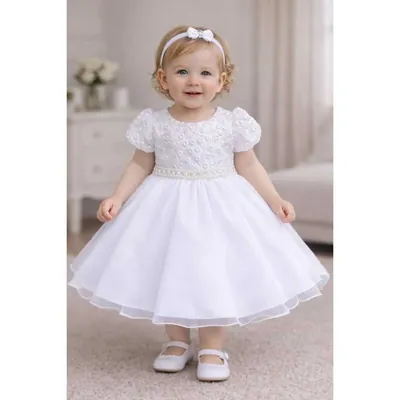 Menina pequena com vestido branco de mangas bufantes, corpo com pérolas, cinto de pérolas e saia rodada de tule