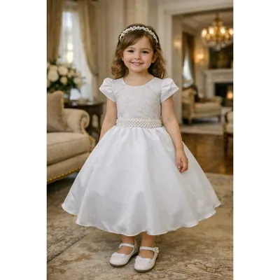 Menina com vestido branco midi, corpinho bordado, mangas bufantes, cinto de pérolas e tiara, em sala clássica
