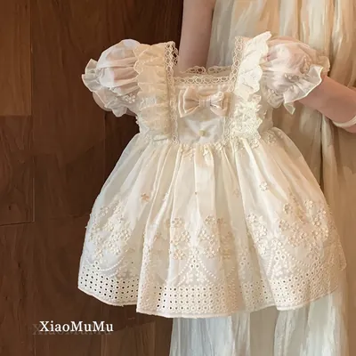 Vestido infantil creme com mangas bufantes, decote quadrado com renda, laço no peito e saia bordada com barra de laise