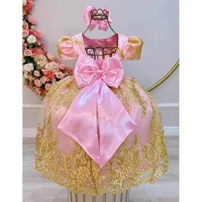 Vestido infantil rosa de cetim com renda dourada, mangas bufantes e laço grande nas costas, em manequim de arame dourado
