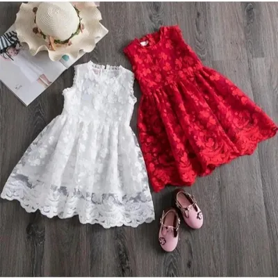 Dois vestidos infantis de renda floral sem mangas, um branco e um vermelho, ao lado de sapatilhas rosa e chapéu de palha
