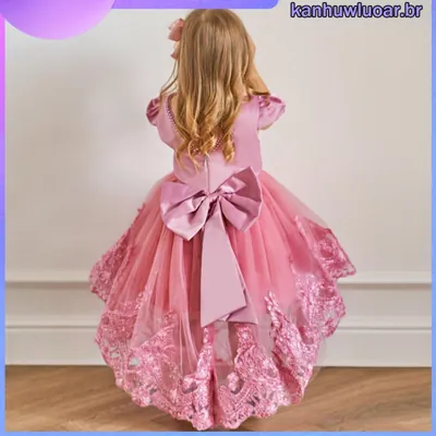 Menina de costas usando vestido rosê com mangas bufantes, laço grande de cetim e saia de tule com barra de renda