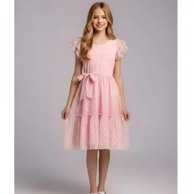 Adolescente com vestido rosa claro midi, tecido com desenho ondulado branco, mangas de babado e faixa amarrada em laço
