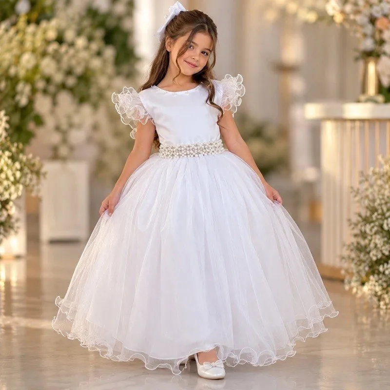Menina com vestido longo branco, mangas de babado, cinto de contas peroladas e saia de tule rodada em salão com flores