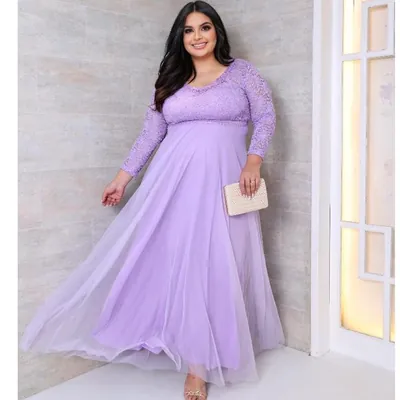 Mulher plus size em vestido longo lilás com corpo e mangas de renda, saia de tule esvoaçante e clutch de palha na mão