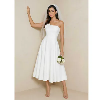Mulher de véu curto e buquê de rosas brancas usando vestido midi off-white com laço no ombro e saia rodada
