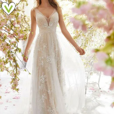 Noiva com vestido fluido de tule e apliques de renda, decote em V e cintura bordada, entre galhos de flores rosadas