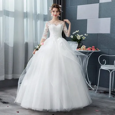 Noiva com vestido branco de princesa, corpete de renda, mangas 3/4 transparentes e saia volumosa de tule em camadas