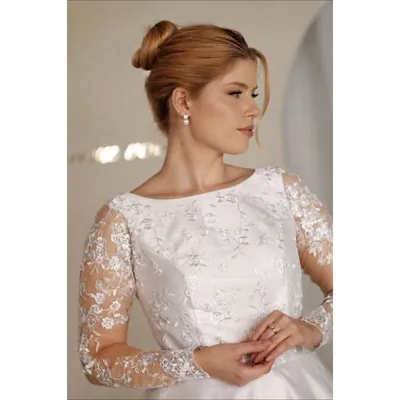 Noiva de coque com vestido de decote canoa, corpete bordado com flores e mangas longas transparentes de renda