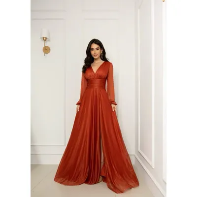 Mulher com vestido longo terracota de tule brilhoso, decote V, mangas longas transparentes, faixa na cintura e fenda
